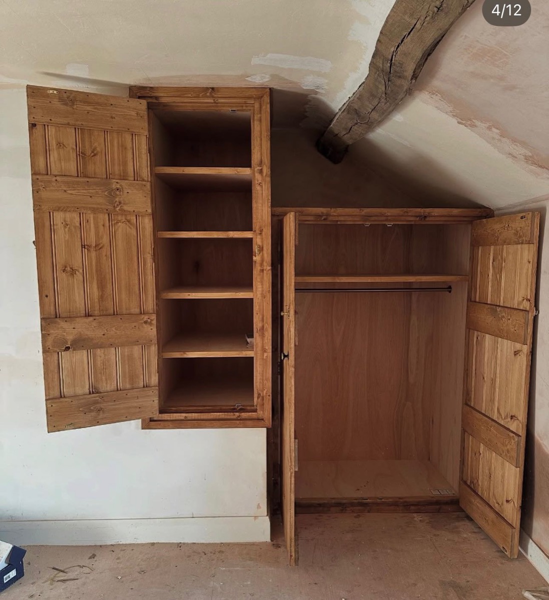 Pine fitted wardrobe under sloping ceiling with open doors showing interior