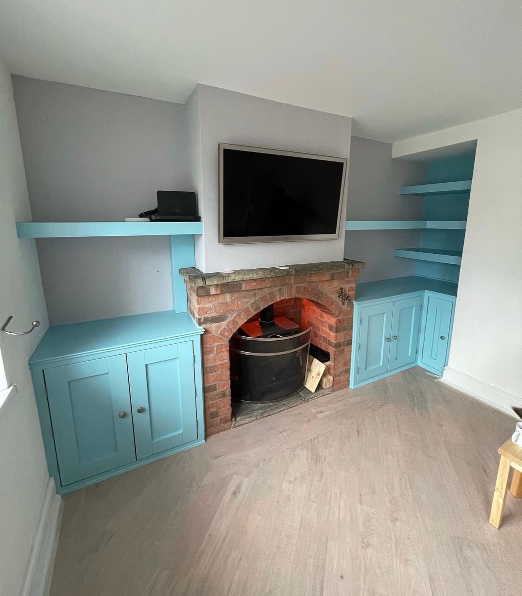 Teal painted bespoke alcove units with cabinet doors flanking fireplace