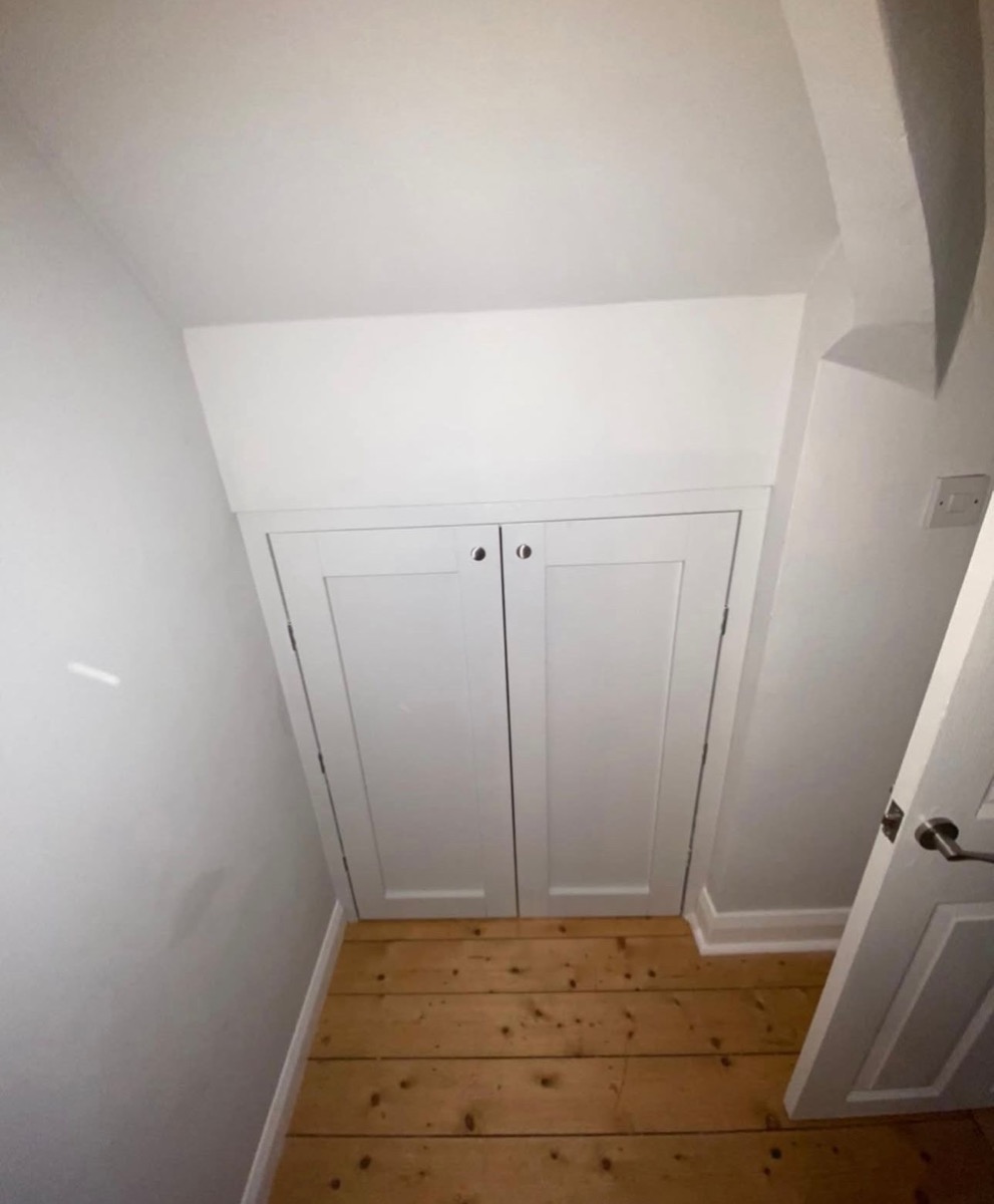 White fitted cupboard built under sloping staircase, bespoke Liverpool joinery