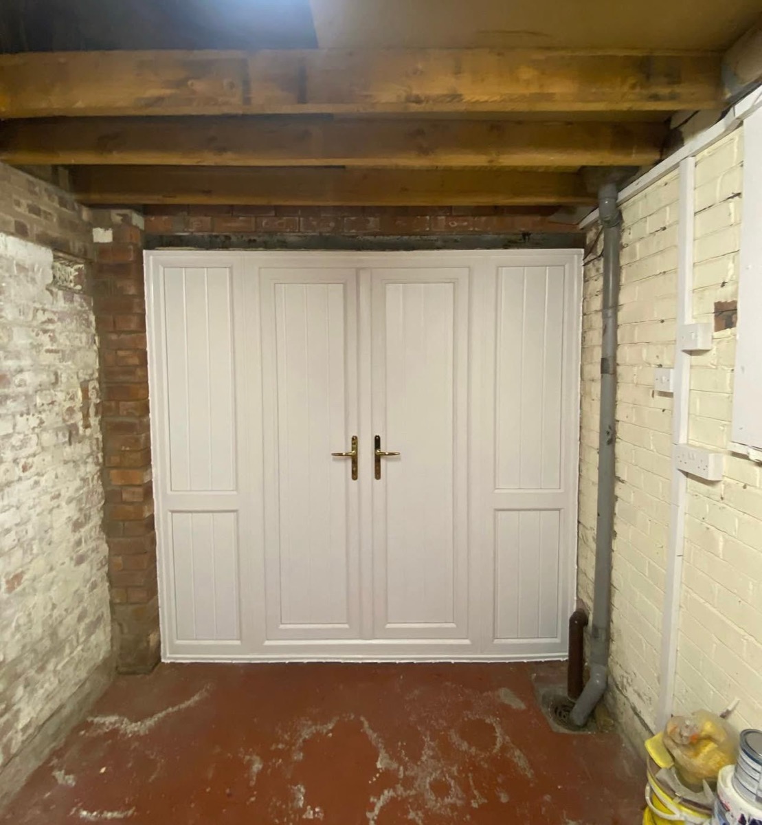 White bespoke double doors with ring handles fitted in brick outbuilding