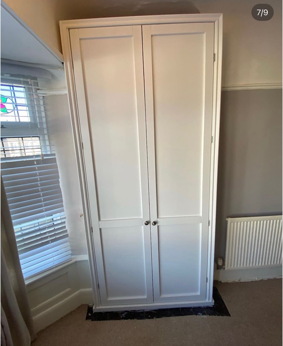 White fitted wardrobe in period bedroom with stained glass bay window